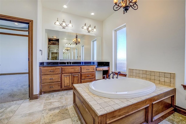 bathroom with vanity, an inviting chandelier, and a washtub