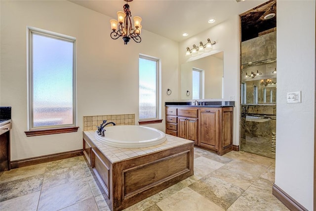 bathroom featuring vanity, an inviting chandelier, and a relaxing tiled tub