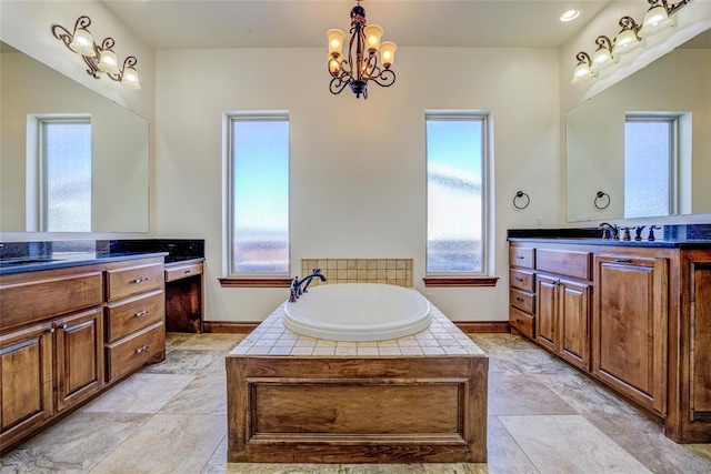 bathroom featuring tiled bath, a healthy amount of sunlight, vanity, and a chandelier