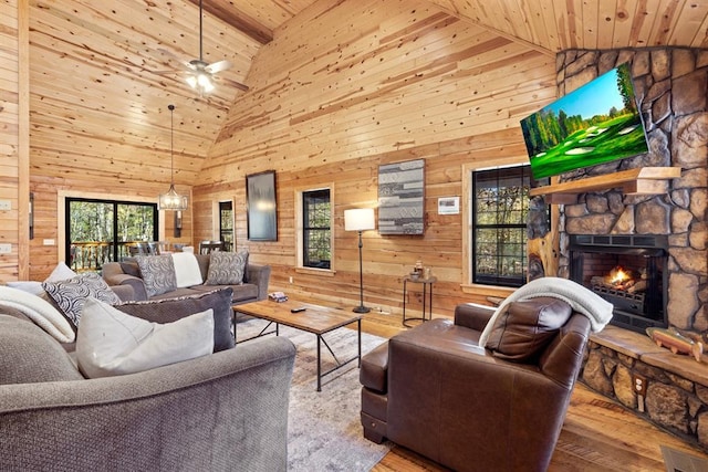 living room with a fireplace, wood walls, high vaulted ceiling, and wood ceiling