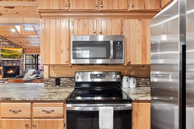 kitchen with light stone counters, backsplash, stainless steel appliances, and a fireplace