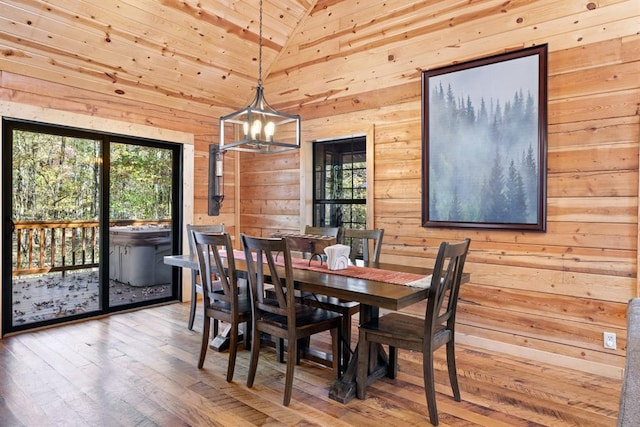 dining area with wood-type flooring, wood ceiling, high vaulted ceiling, a notable chandelier, and wood walls