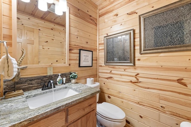 bathroom featuring toilet, wood ceiling, wooden walls, and vanity