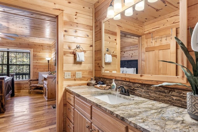 bathroom featuring wooden ceiling, vanity, and wood walls