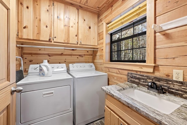 washroom with sink, separate washer and dryer, wood walls, and cabinets