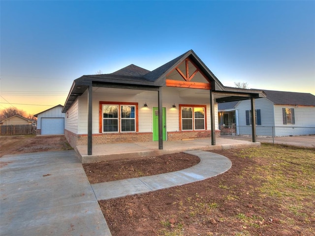 back house at dusk featuring a garage and an outdoor structure