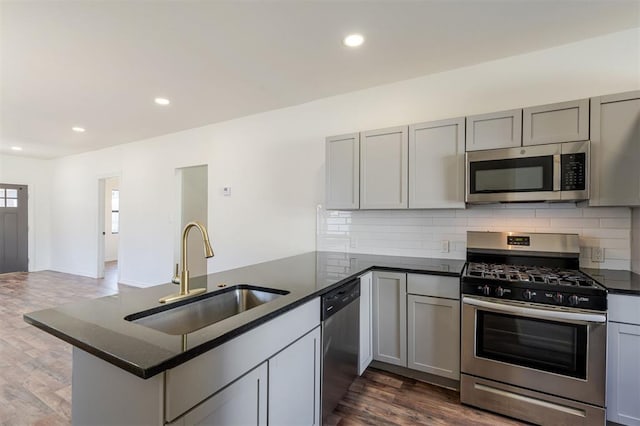 kitchen with sink, appliances with stainless steel finishes, gray cabinets, and kitchen peninsula