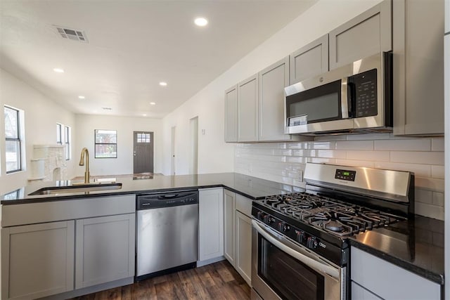 kitchen with stainless steel appliances, gray cabinetry, kitchen peninsula, and sink