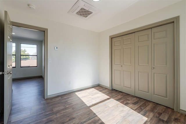 unfurnished bedroom featuring a closet and dark hardwood / wood-style flooring