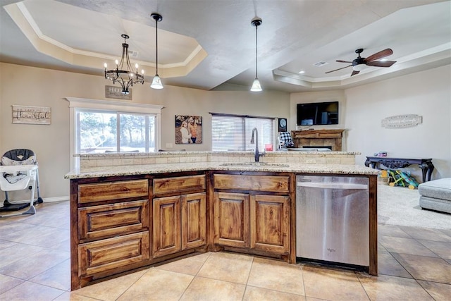 kitchen featuring stainless steel dishwasher, decorative light fixtures, sink, and a tray ceiling