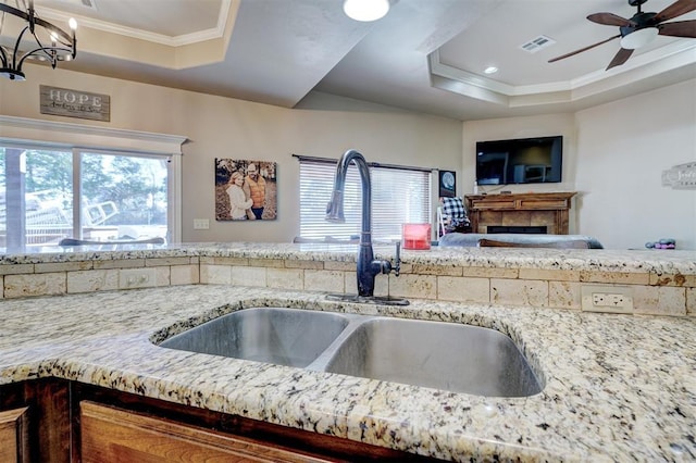 kitchen featuring crown molding, ceiling fan with notable chandelier, a tray ceiling, and sink