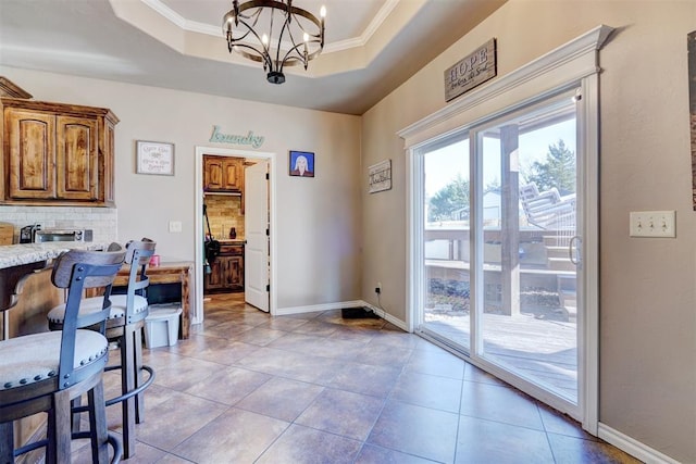 doorway with an inviting chandelier, crown molding, and a tray ceiling