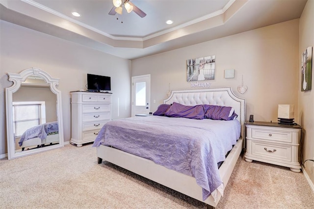 carpeted bedroom with ceiling fan, a tray ceiling, and ornamental molding