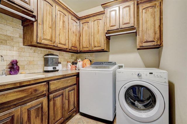 washroom featuring washer and dryer, cabinets, light tile patterned floors, and sink