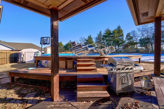 view of patio / terrace featuring a pool side deck with water view, a grill, and a storage unit