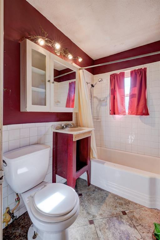 full bathroom with tile walls, toilet, vanity, and shower / bath combo