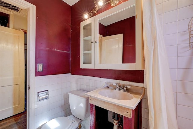 bathroom with toilet, tile walls, sink, and hardwood / wood-style floors