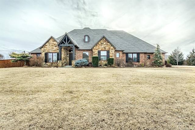 craftsman house featuring stone siding, brick siding, and a front yard