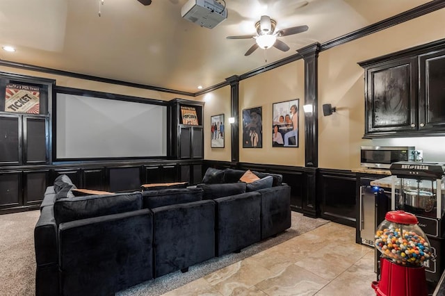 cinema featuring a ceiling fan, a wainscoted wall, ornamental molding, ornate columns, and a decorative wall