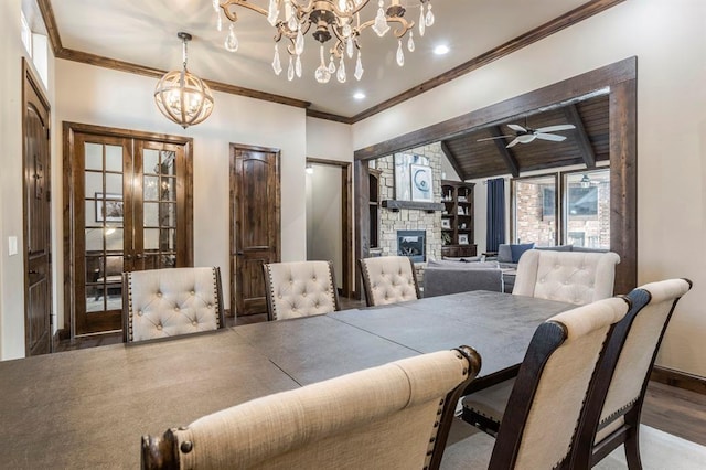 dining area with crown molding, a fireplace, ceiling fan with notable chandelier, and lofted ceiling with beams