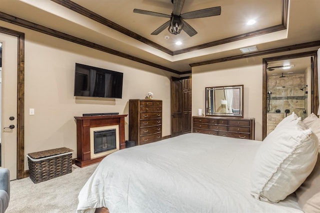 carpeted bedroom featuring a glass covered fireplace, a raised ceiling, visible vents, and crown molding