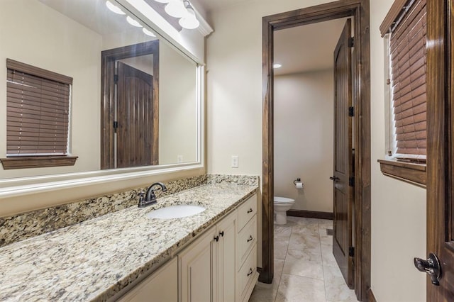 bathroom featuring vanity, toilet, and baseboards