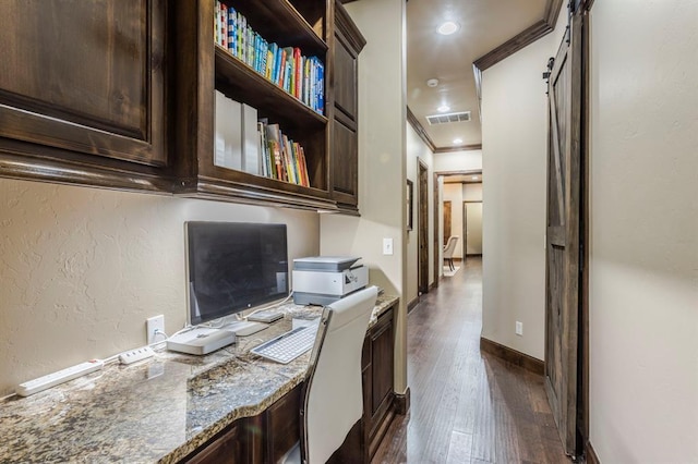 office with a barn door, visible vents, baseboards, ornamental molding, and dark wood finished floors