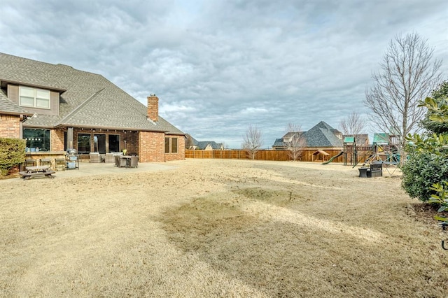 view of yard with a patio area, a playground, and a fenced backyard