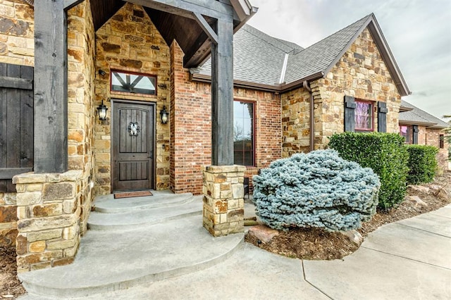 property entrance with stone siding, brick siding, and roof with shingles