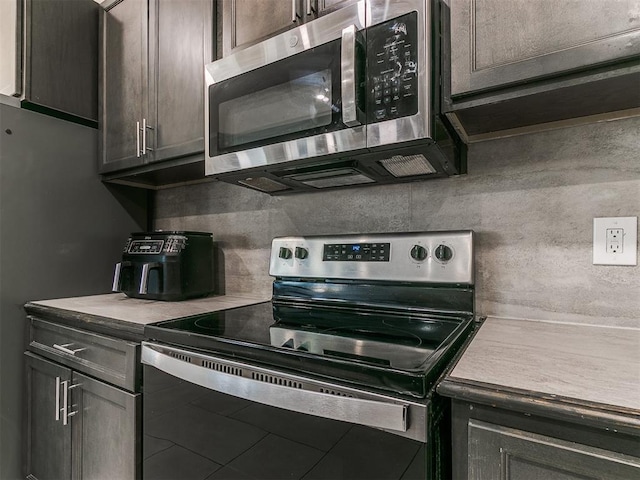 kitchen featuring stainless steel appliances, dark brown cabinets, and backsplash