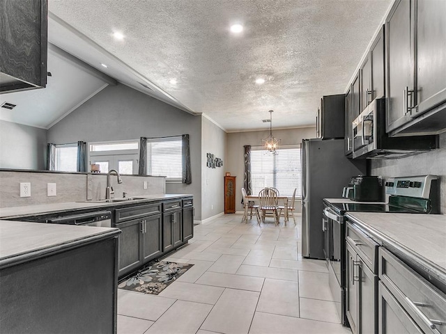 kitchen with a textured ceiling, appliances with stainless steel finishes, lofted ceiling, a notable chandelier, and light tile patterned floors