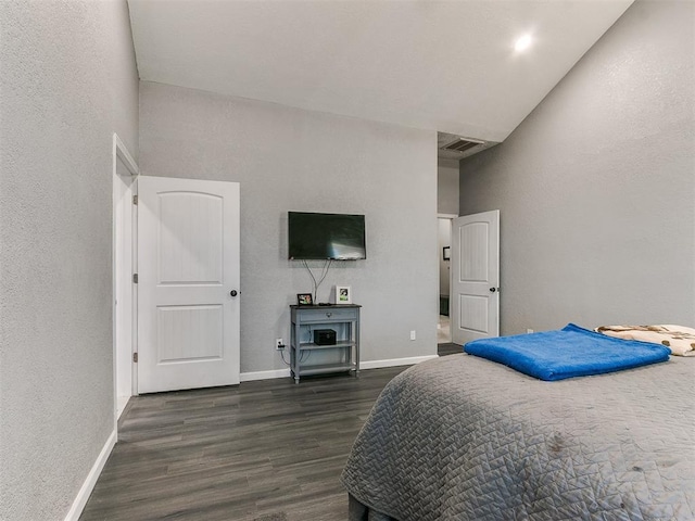 bedroom featuring a towering ceiling and dark hardwood / wood-style flooring