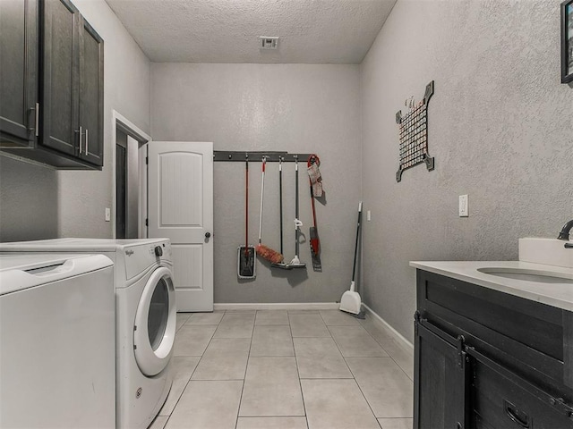 washroom with independent washer and dryer, sink, a textured ceiling, light tile patterned floors, and cabinets