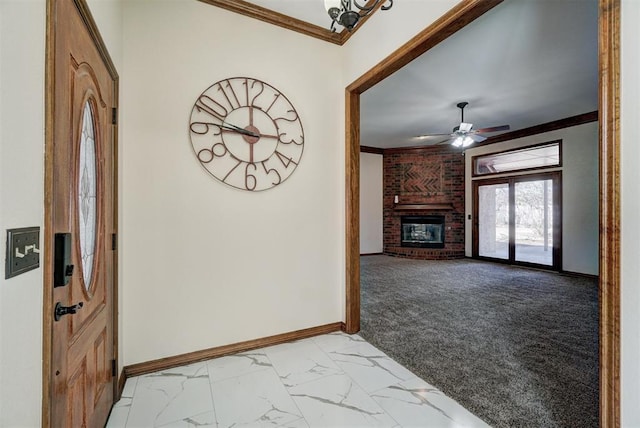 carpeted entrance foyer featuring ceiling fan, crown molding, and a fireplace