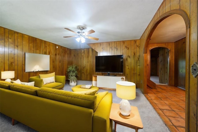 tiled living room with ceiling fan and wooden walls