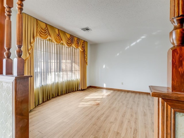 unfurnished living room with light wood-type flooring and a textured ceiling