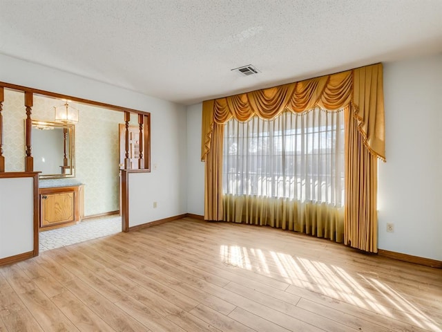 spare room featuring a textured ceiling and light hardwood / wood-style flooring