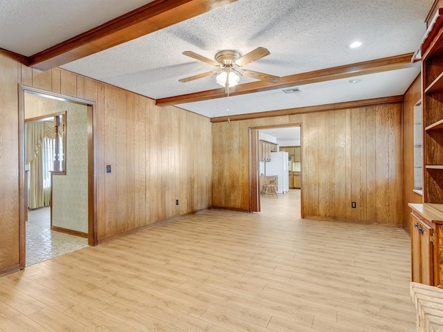 empty room featuring a textured ceiling, ceiling fan, and beamed ceiling