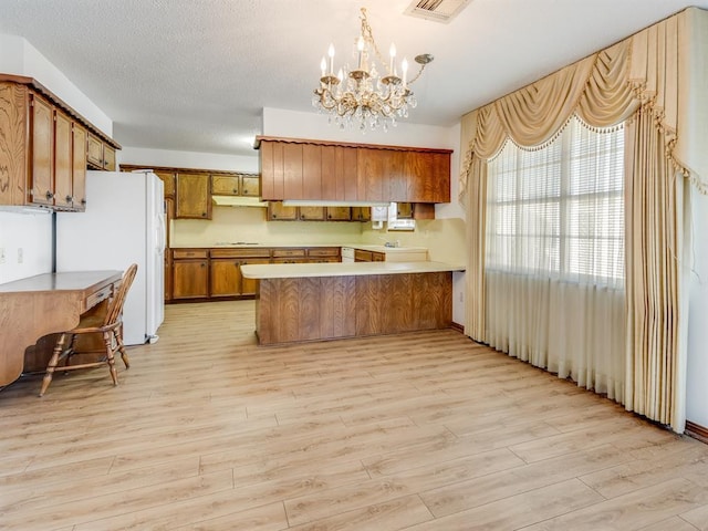 kitchen featuring decorative light fixtures, kitchen peninsula, light hardwood / wood-style flooring, white refrigerator, and a chandelier