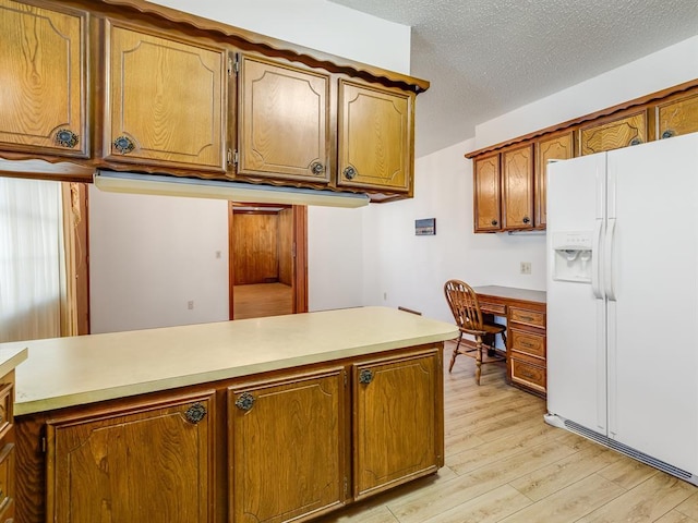 kitchen with white fridge with ice dispenser, a textured ceiling, built in desk, kitchen peninsula, and light hardwood / wood-style flooring