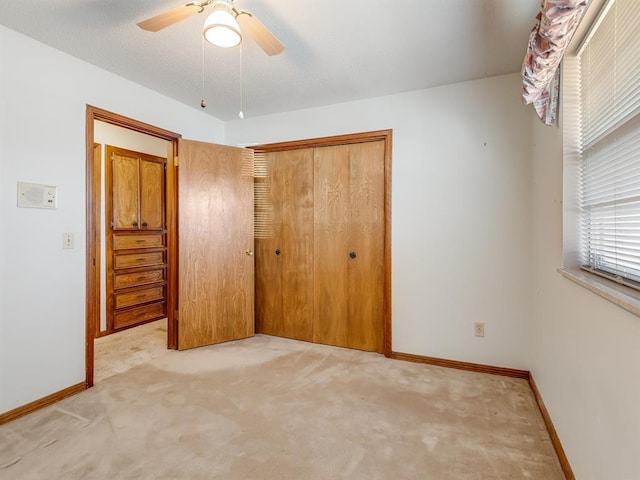 unfurnished bedroom featuring light carpet, ceiling fan, and a closet