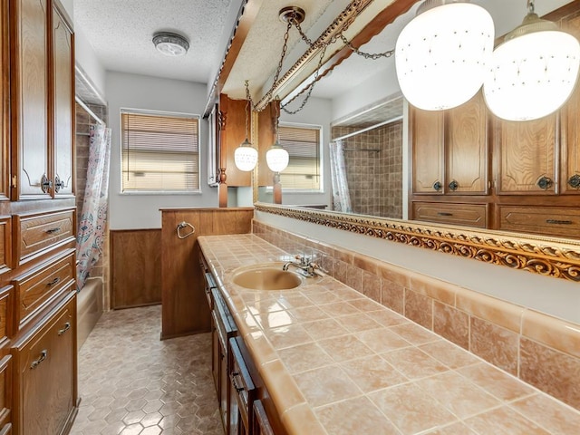 bathroom with vanity, plenty of natural light, wooden walls, and a textured ceiling