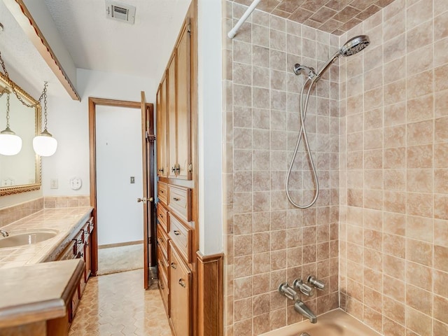 bathroom with tiled shower / bath and vanity