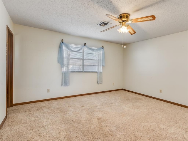 empty room featuring ceiling fan, light colored carpet, and a textured ceiling