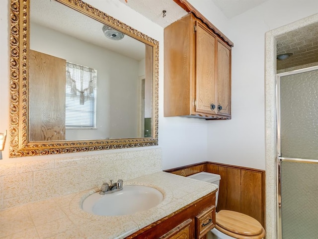 bathroom featuring toilet, walk in shower, wood walls, and vanity