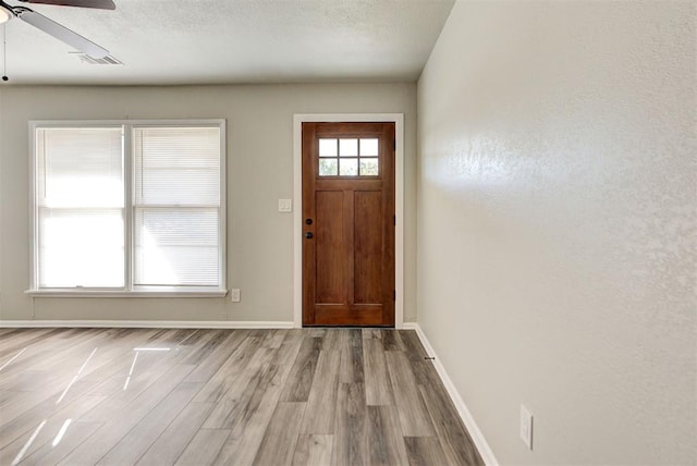 foyer with light wood-type flooring, ceiling fan, and a textured ceiling