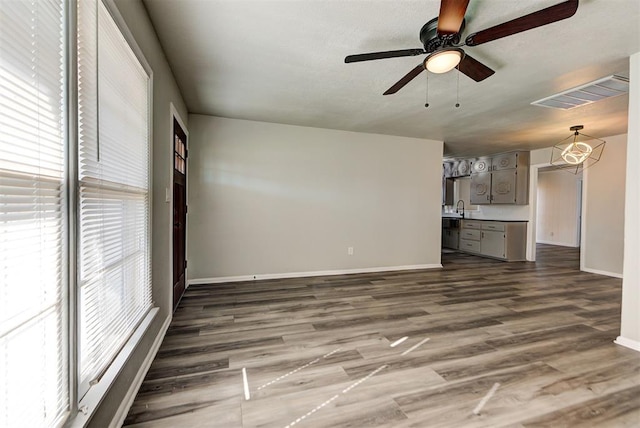 unfurnished living room with sink, ceiling fan with notable chandelier, and hardwood / wood-style floors