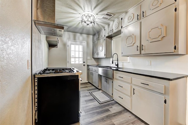 kitchen featuring a textured ceiling, range with gas stovetop, light hardwood / wood-style flooring, and sink