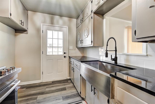 kitchen with hardwood / wood-style flooring, sink, white cabinetry, and decorative backsplash