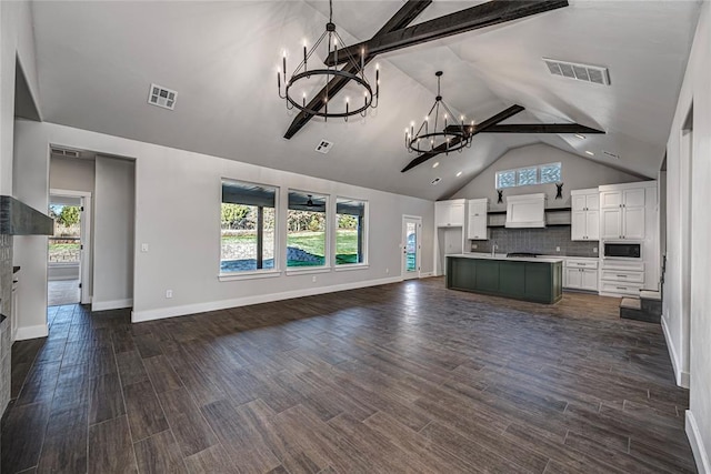 unfurnished living room featuring lofted ceiling with beams, dark hardwood / wood-style floors, and an inviting chandelier